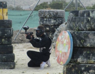  boy hiding behind wheels playing paintball 